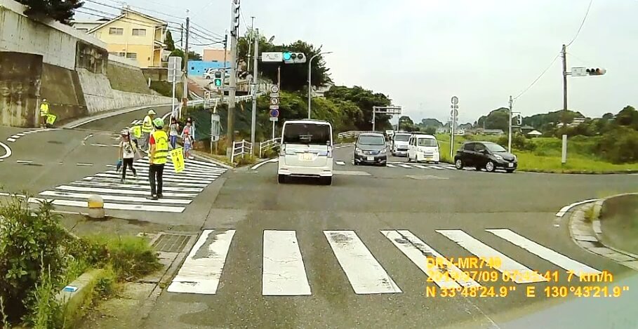 七重町入口の信号横断歩道を渡る子どもたち、旗ふりをしている地域の方の写真