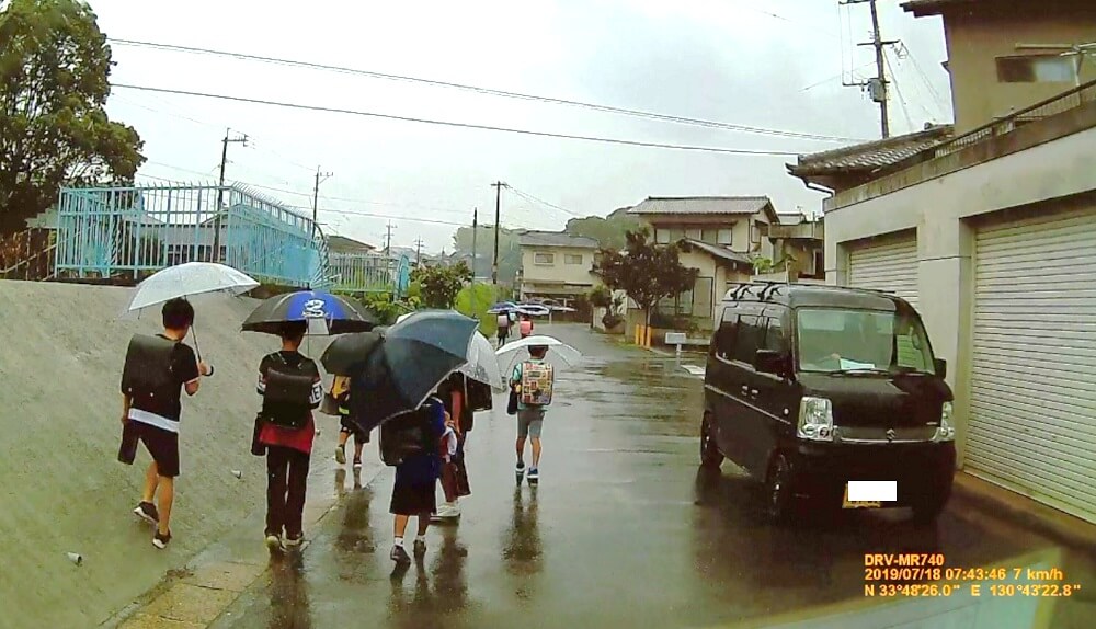 7月18日は雨で、大辻町通学路を登校する子どもたちの写真