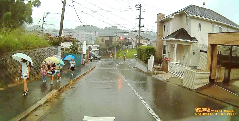 7月18日は雨で、弥生2丁目通学路を登校する子どもたちの写真