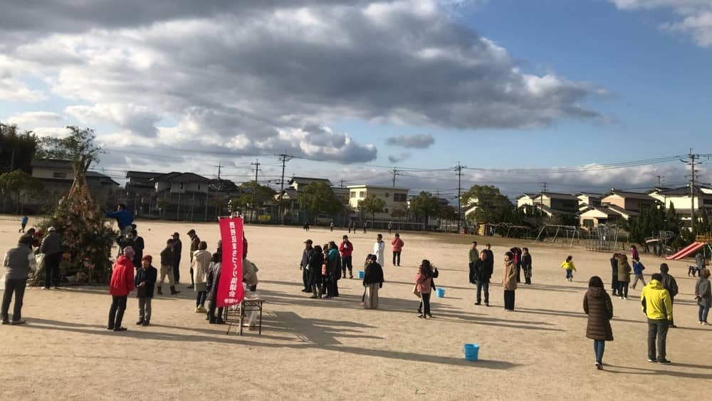 地域の方がどんどやぐらにしめ縄を持ってきている写真