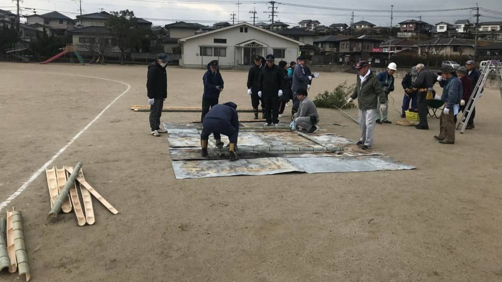 鉄板の上で竹を組み始めている写真