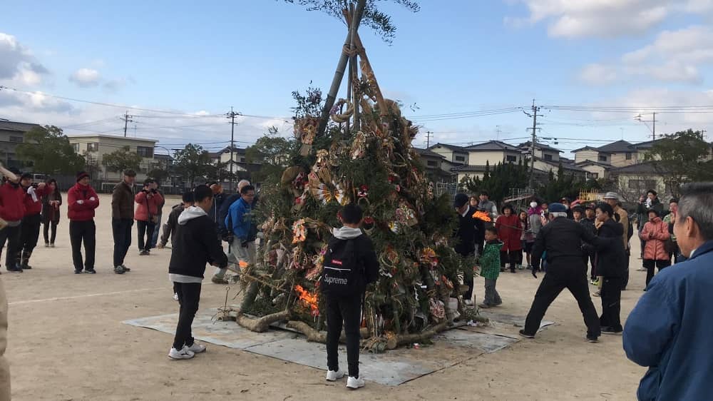 児童代表がどんどやぐらの下の部分に点火している写真